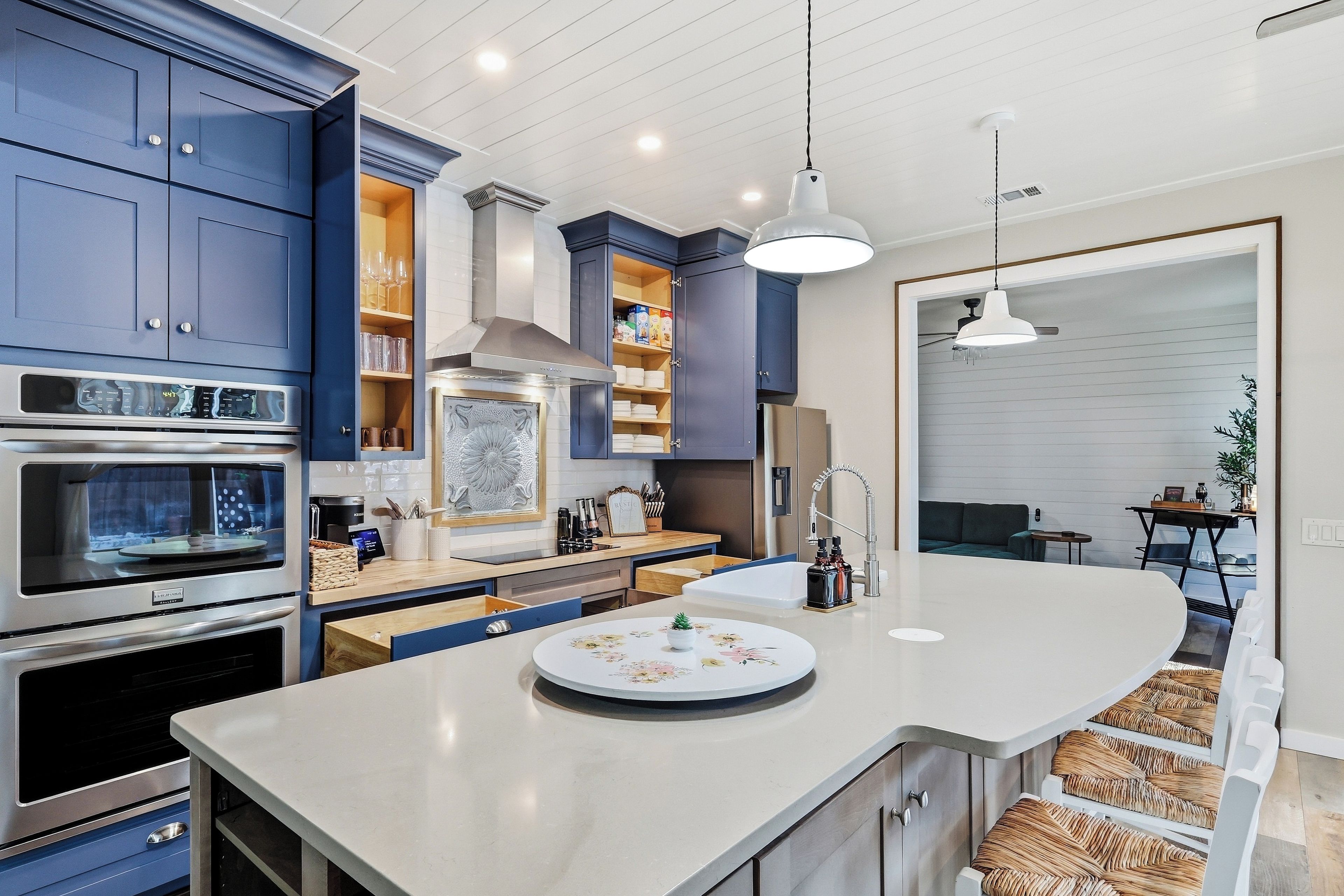 A modern kitchen with built-in appliances, a central island, and a dining area with a sofa.
