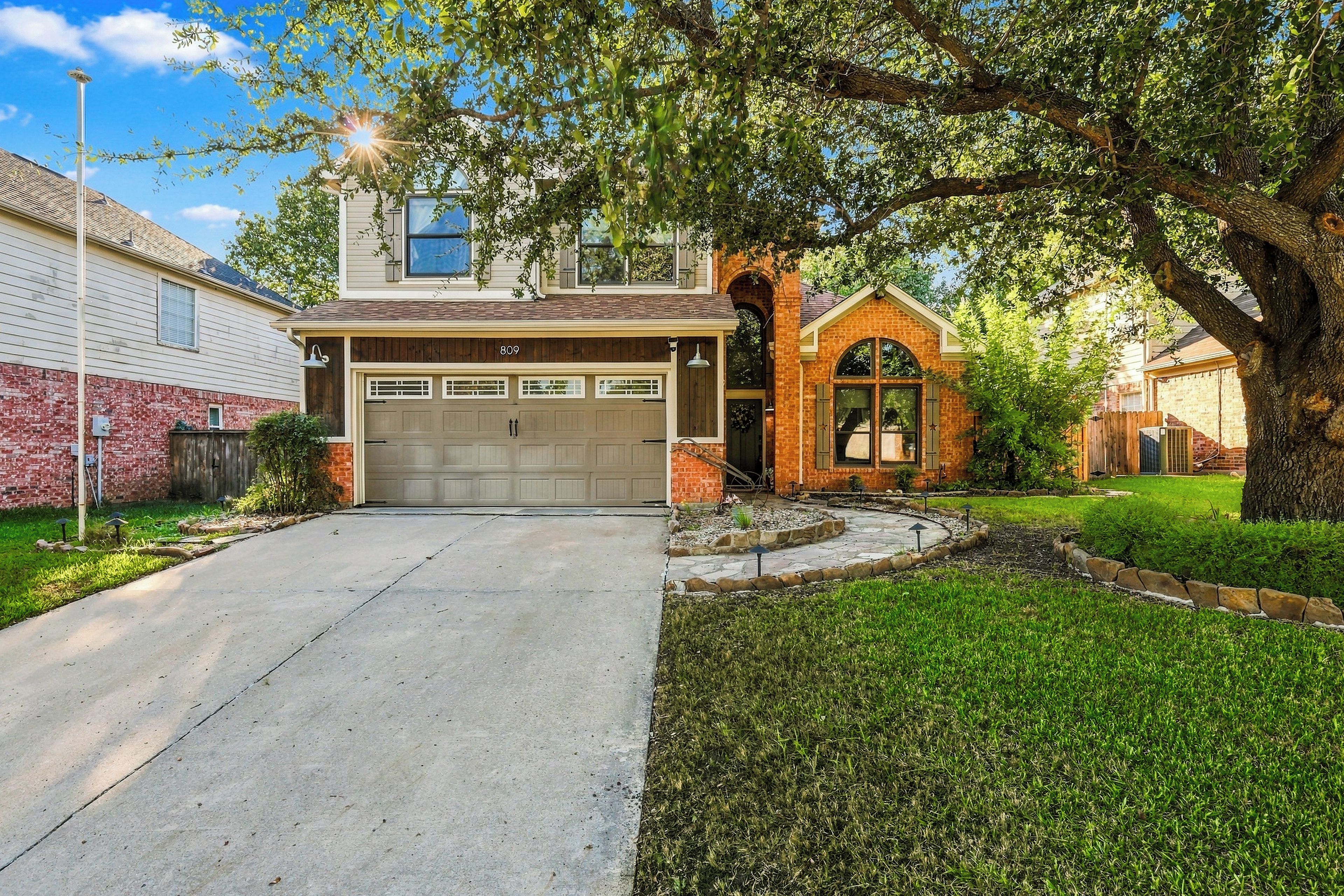 A residential property with a garage, a brick house, and a well-maintained lawn.