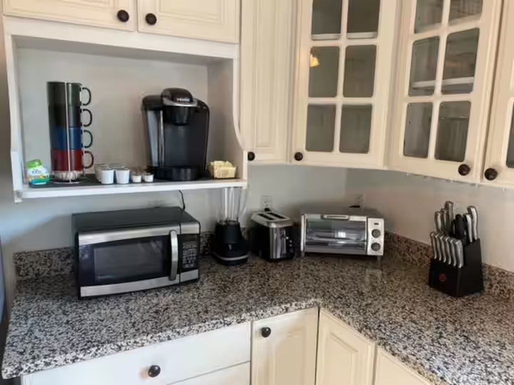 A kitchen with a microwave, toaster, coffee maker, and knife block.