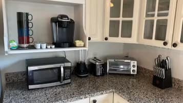 Een keuken met een magnetron, broodrooster, koffiezetapparaat en messenblok.