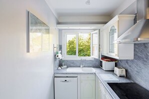 Eine moderne Küche mit Backofen, Spüle und einem Fenster mit Blick auf Grünflächen.