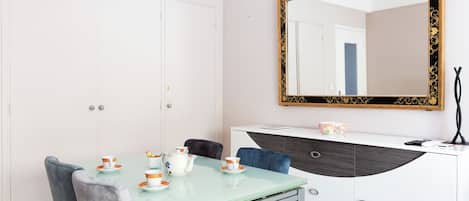 A dining area with a glass table, chairs, and a white cabinet with a mirror.