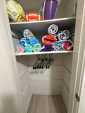 Un placard de rangement avec des étagères où sont pliés des serviettes et rangés des ballons de sport.