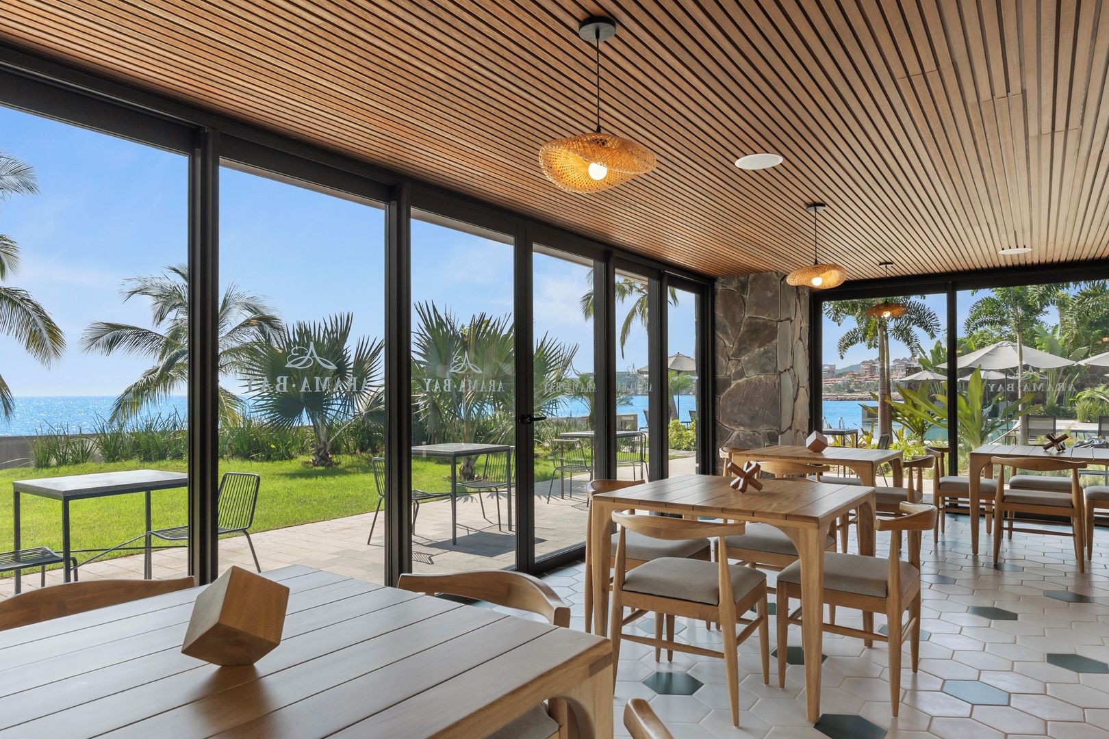 Un restaurante con amplios ventanales, mesas de madera y vistas al mar.