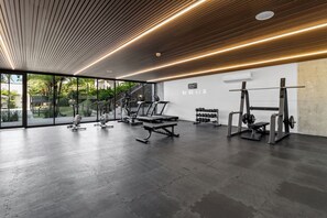 Un gimnàs modern amb equipament d'exercici, grans finestres i un sòl de formigó.
