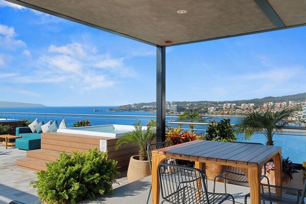Eine Terrasse mit Pool, Sitzgelegenheit und Blick auf das Meer und die Gebäude.
