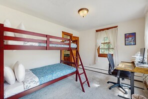 Una cama litera con escalera, un escritorio con silla, una ventana con cortinas y un cartel en la pared.