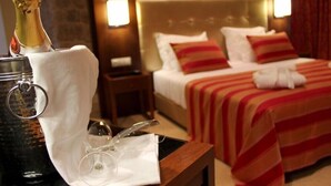 A hotel room with a bed, bedside lamps, a bottle of champagne, and a glass on a tray. - Palace Hotel & SPA Termas DE SAO Tiago (Penamacor)