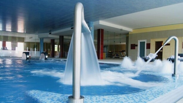 A modern indoor swimming pool with a central water feature and a tiled floor. - Palace Hotel & SPA Termas DE SAO Tiago (Penamacor)