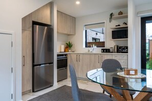 Une cuisine moderne dotée d’appareils électroménagers en acier inoxydable, de meubles en bois et d’une table à manger en verre.