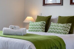 A neatly made bed with green and white patterned pillows, a rolled white towel, and a green throw blanket. - Over The Moon | Quiet CBD w/ Courtyard (Christchurch)