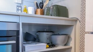 Una cocina con horno empotrado, microondas y varios electrodomésticos en estantes.