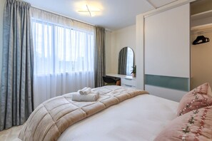 Un dormitorio con cama, escritorio, espejo y armario.