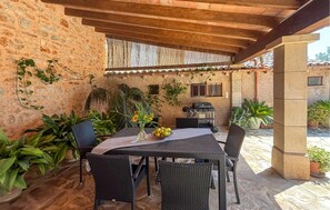 Eine Terrassengruppe im Freien mit Tisch und Stühlen, umgeben von Blumentöpfen und einer Steinmauer.