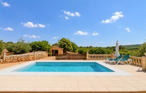 A swimming pool with a stone wall, a wooden fence, and a view of the countryside. - Awesome home in Manacor with private swimming pool, can be inside or outside (Manacor)