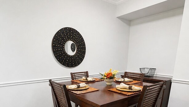 Un coin repas comprenant une table ronde, six chaises et un miroir décoratif fixé au mur.