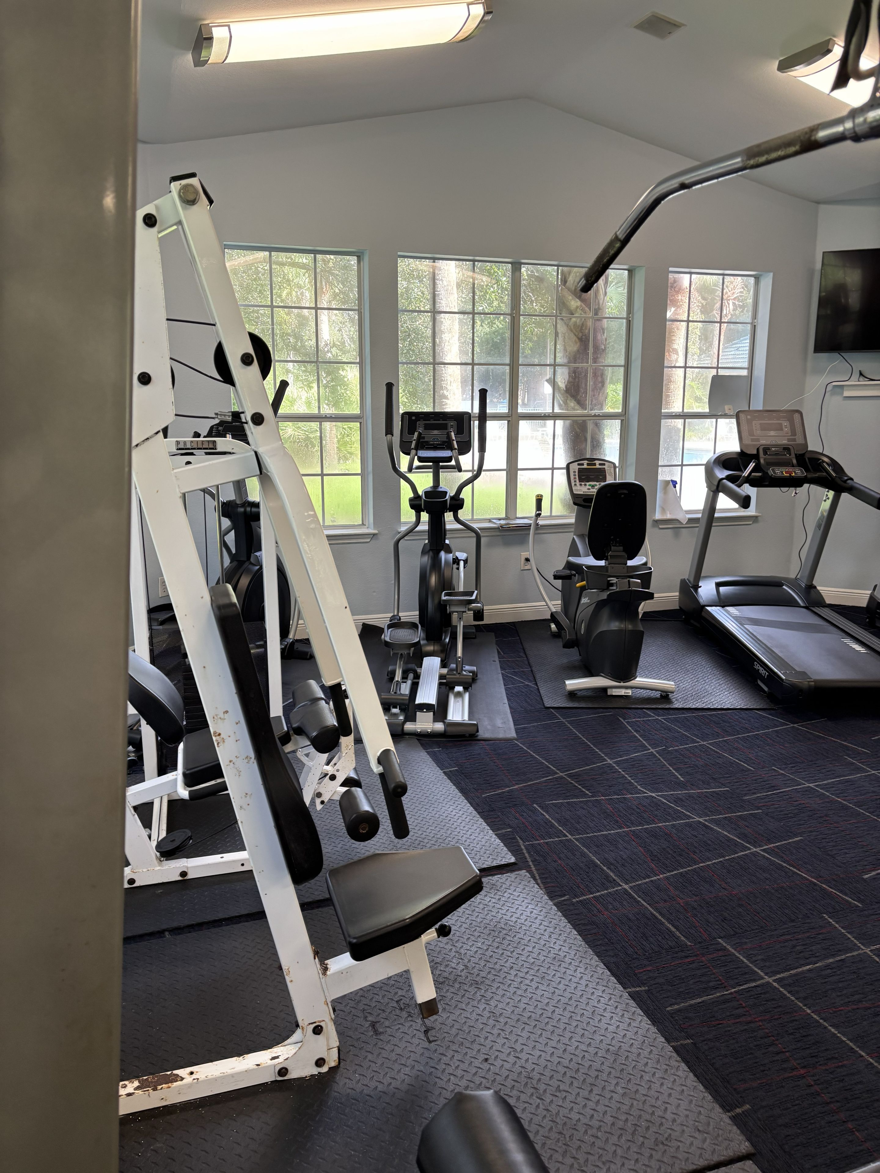 A gym with various exercise equipment, large windows, and a treadmill.