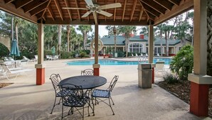 Un espace extérieur abrité comprenant une piscine, des chaises longues et une table avec des chaises.