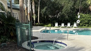 Un espace piscine agrémenté d’un panneau indiquant qu’il est interdit de plonger, de chaises longues et d’un palmier.