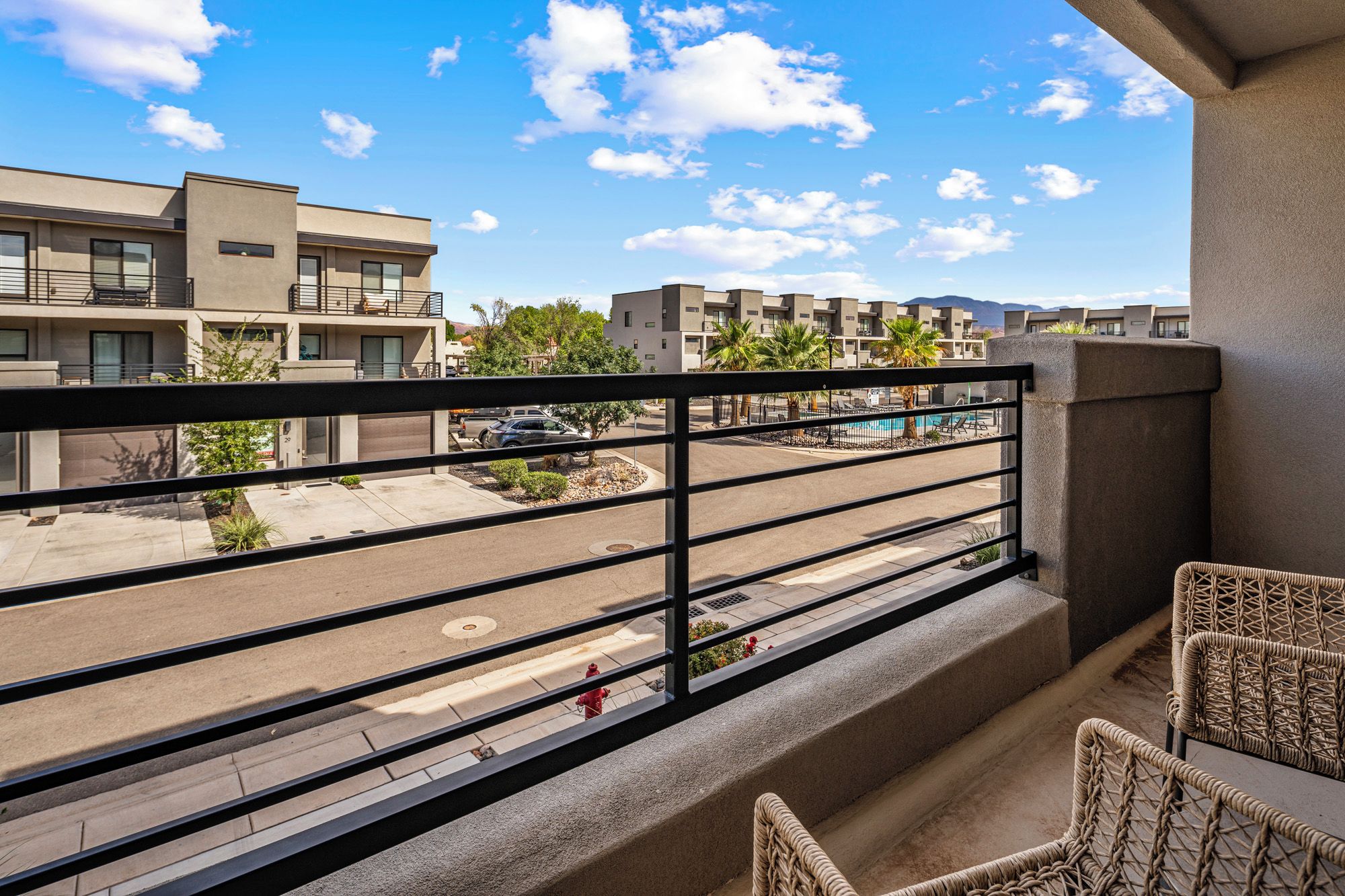 Un balcon donnant sur un parking et des immeubles.