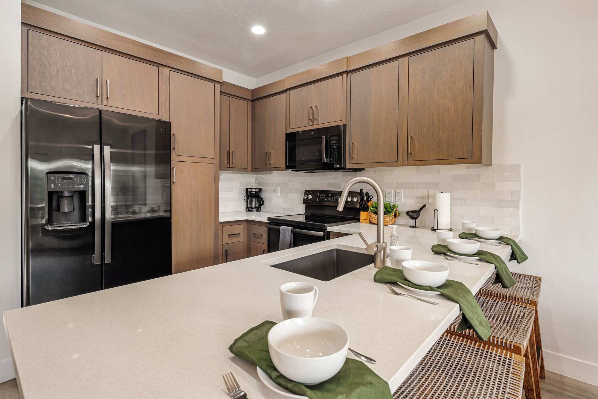 A modern kitchen with stainless steel appliances, wooden cabinets, and a central island with seating.