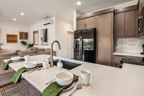 A modern kitchen with a central island, stainless steel appliances, and wooden cabinets. - The Vue 5, Resort Pool, Private Balcony, Grill (Saint George)