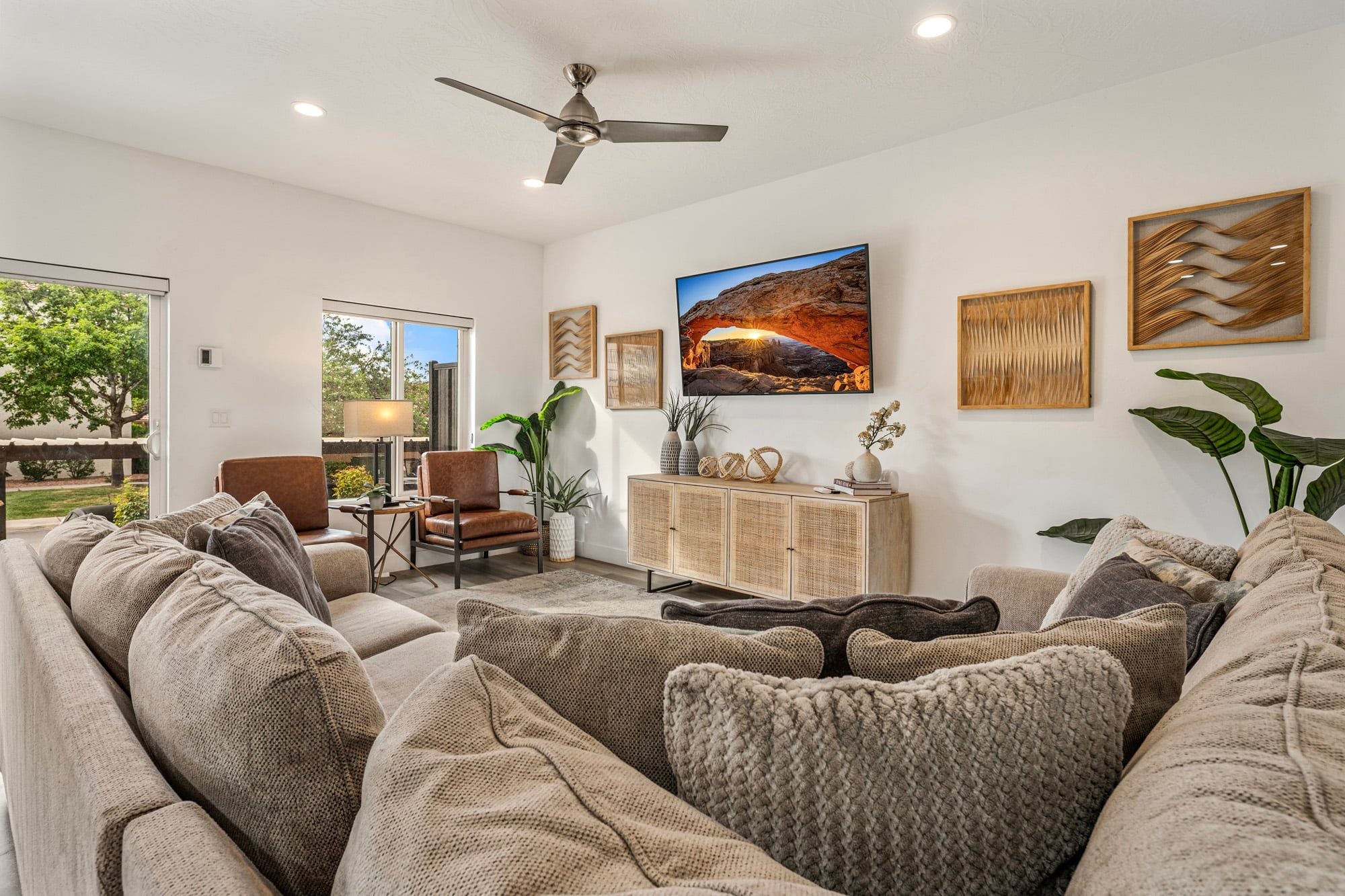 A modern living room with a sofa set, a wooden cabinet, and a ceiling fan.