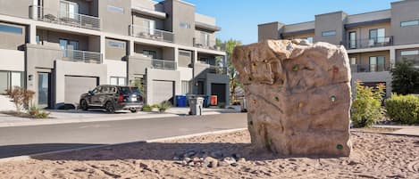 A modern apartment building with multiple balconies and a large rock sculpture in the foreground.