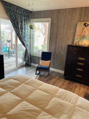 A bedroom with a large bed, a chair, a dresser, and a window with curtains.
