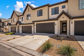 A residential building with multiple garage doors, a driveway, and a landscaped front yard with gravel and plants. - Skyline 1753, Private Hot Tub, Resort Amenities, and Close to Sand Hollow! (Washington)
