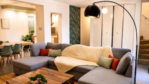 Un salon moderne avec un canapé d’angle, une table basse en bois et un lampadaire.
