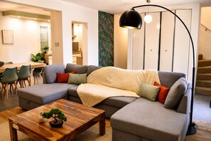 Ein modernes Wohnzimmer mit einer Eckcouch, einem Holztisch und einer Stehlampe.
