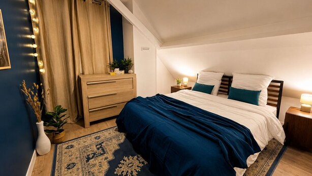 Une chambre à coucher comprenant un lit, des tables de chevet, une commode, un miroir et un luminaire au plafond.