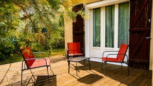 Une terrasse en bois avec deux chaises rouges et une table.