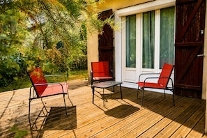 Eine Holzterrasse mit zwei roten Stühlen und einem Tisch.