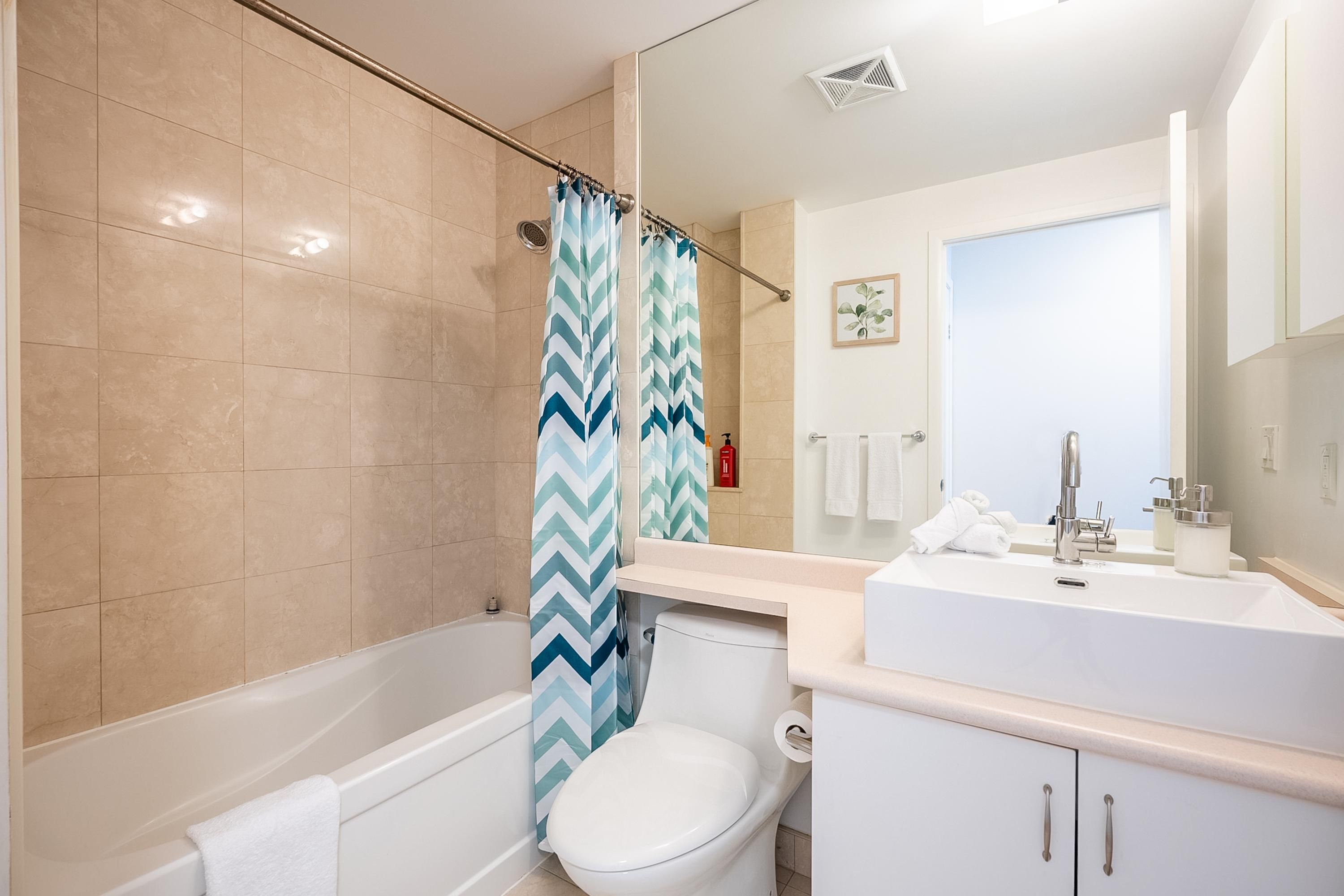 A modern bathroom with a bathtub, toilet, and sink.