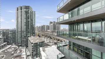 A modern high-rise building with a glass facade, a rooftop terrace, and a view of the cityscape.