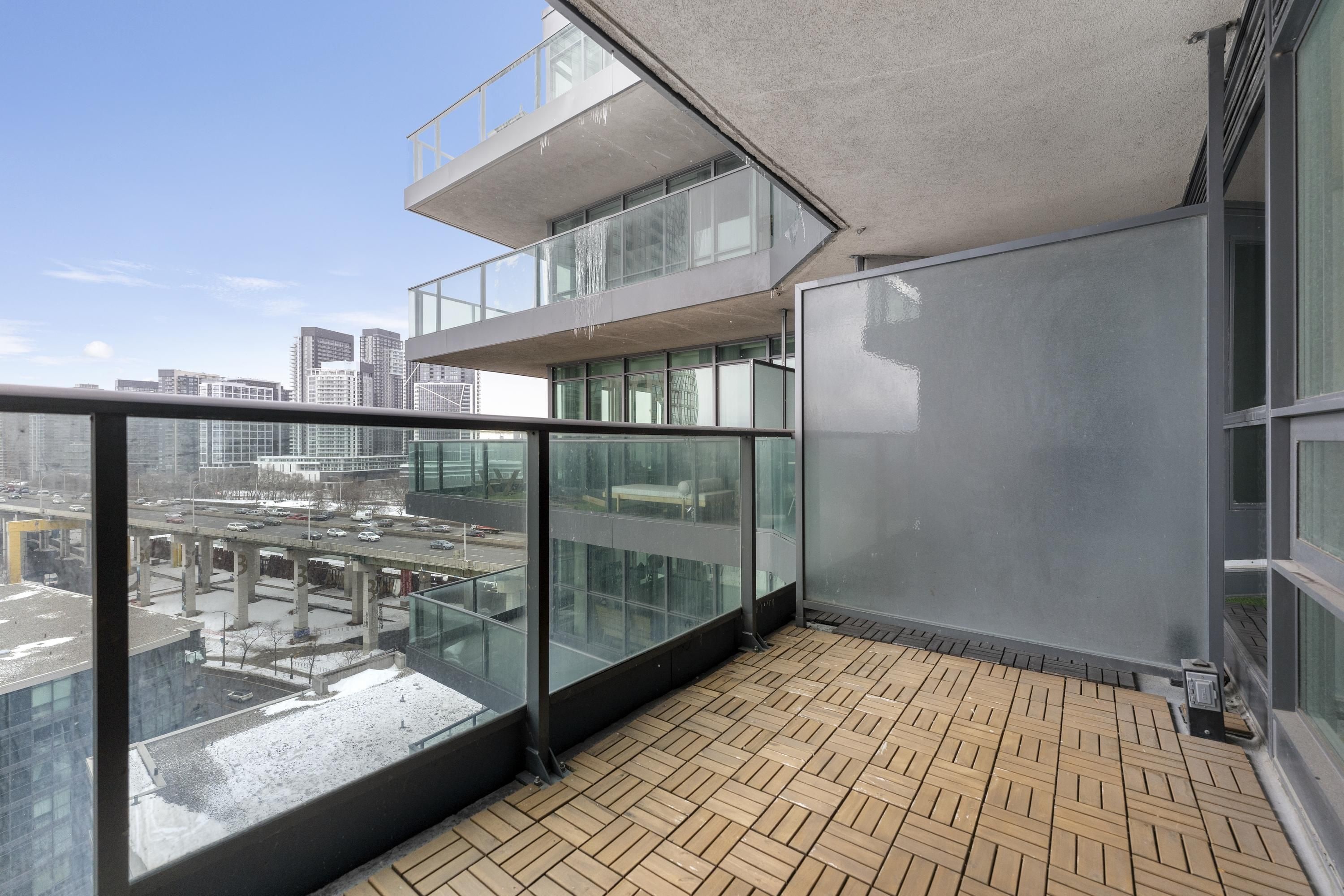 A modern building with a glass balcony, a tiled floor, and a view of a cityscape.