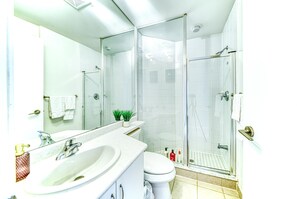 A modern bathroom with a glass-enclosed shower, a white sink, and a toilet. - StayToronto - Fort York Downtown Suites (Toronto)