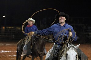 A rodeo event with a cowboy on a horse, holding a lasso.