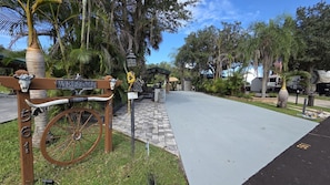 A paved pathway leading to a building entrance with a vintage sign and a bicycle wheel.