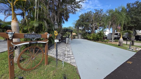 Un chemin pavé menant à l’entrée d’un bâtiment, avec une enseigne ancienne et une roue de vélo.
