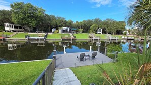 A tranquil outdoor area with a water feature, seating, and RVs parked nearby. - Waterfront RV Oasis: Dock & Pavilion | Lot 561 (River Ranch)