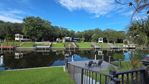 A lakeside view with a dock, chairs, and a small building.