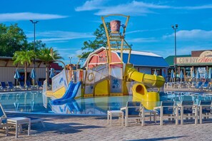 Een waterpark met een groot zwembad, glijbanen en een gebouw in cowboystijl.