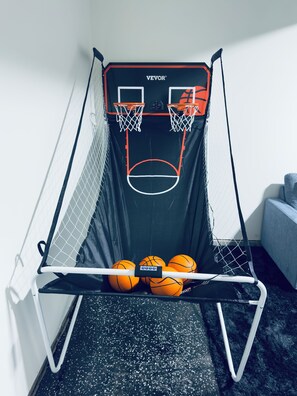 A basketball hoop with a net, two basketballs, and a wall-mounted basketball goal. -     Brand-New Luxury Home Spacious, Stylish & Your Home Away From Home (Tobyhanna)