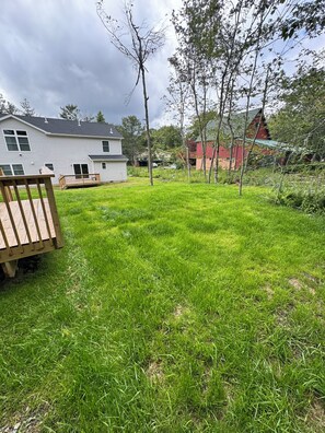A residential backyard with a wooden deck, a white house, and a red barn. -     Brand-New Luxury Home Spacious, Stylish & Your Home Away From Home (Tobyhanna)