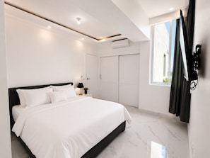 Ein modernes Schlafzimmer mit einem großen Bett, einem Kleiderschrank und einem Fenster mit Vorhängen.