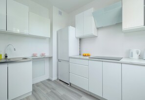 A modern kitchen with white cabinetry, a stainless steel sink, and a built-in oven. - Szczecin Boryny Blossom Studio (Szczecin)