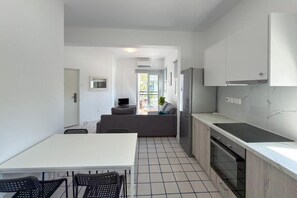 A modern kitchen with a dining area, a built-in oven, and a large window. - Modern 2BR Beach Retreat at Harmony (Germasogeia)
